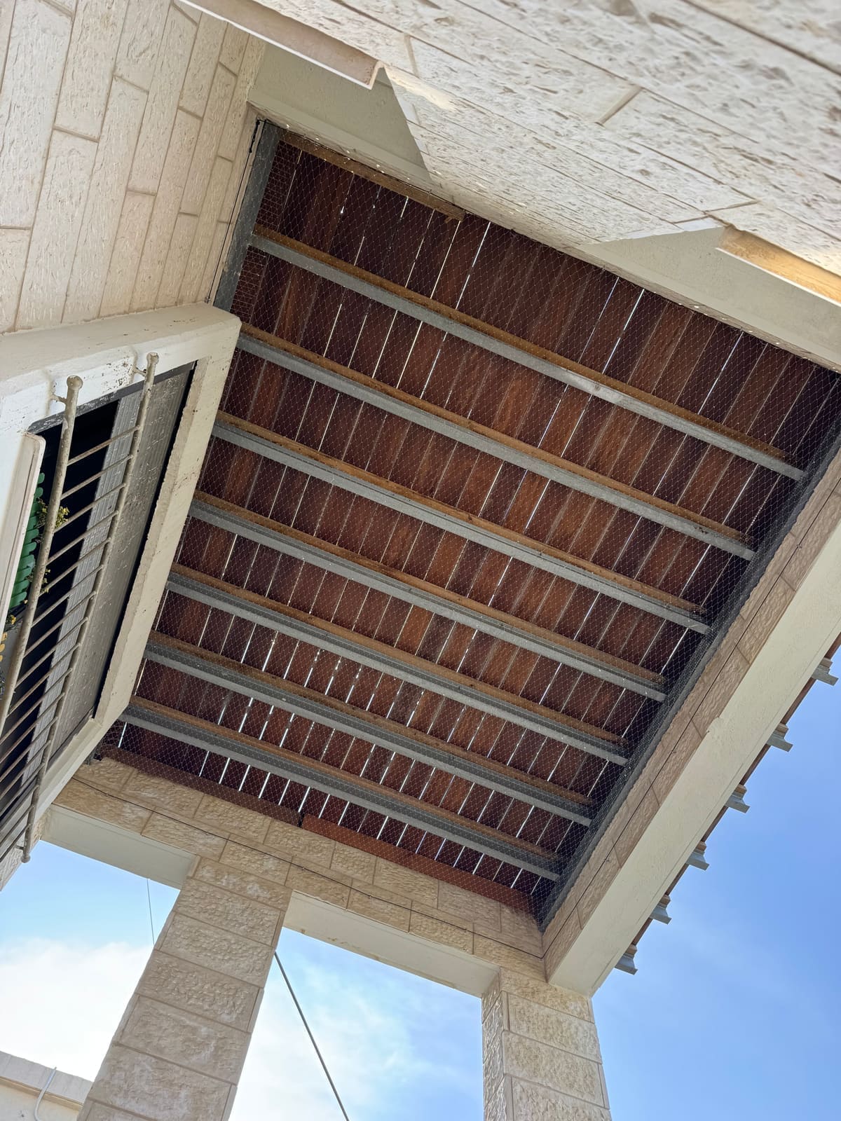 רשת יונים על מרפסת עם נוף לגגות שכנים